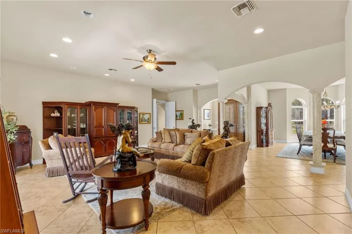 Living area with arched walkways, ornate columns, light tile patterned floors, recessed lighting, and a ceiling fan