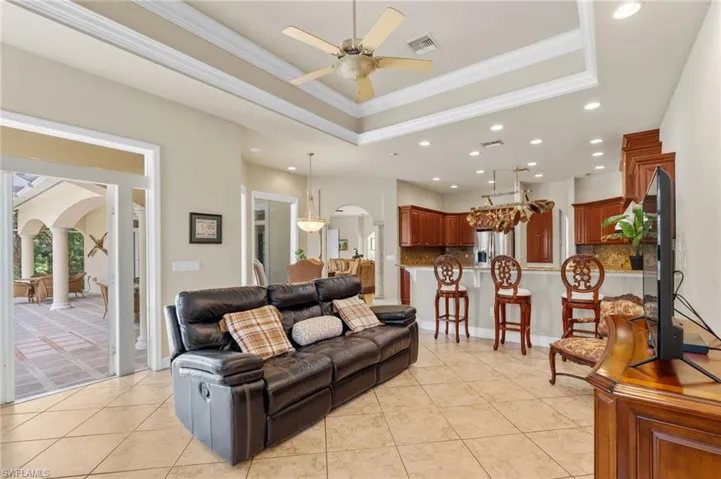Living room featuring arched walkways, recessed lighting, ornamental molding, a raised ceiling, and a ceiling fan