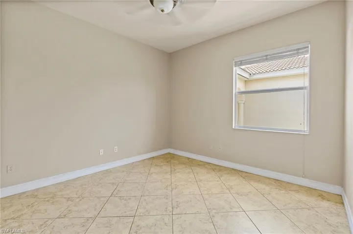 Tiled empty room with a ceiling fan and baseboards