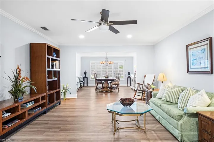 Living area featuring ornamental molding, wood finished floors, visible vents, and baseboards