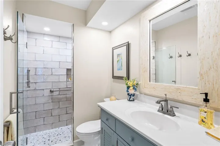 Full bathroom with recessed lighting, a shower stall, toilet, and vanity