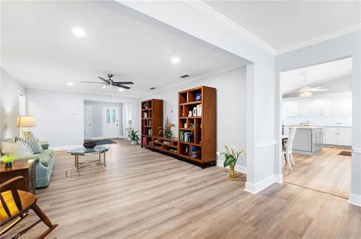 Living area with light wood-style flooring, recessed lighting, a ceiling fan, baseboards, and crown molding