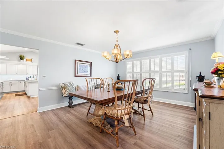 Dining room featuring light wood-style floors, baseboards, visible vents, and crown molding