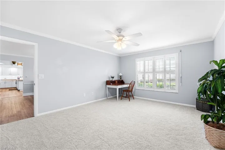 Office with light carpet, crown molding, baseboards, and ceiling fan