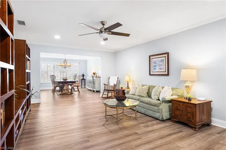 Living room featuring baseboards, visible vents, wood finished floors, and ornamental molding