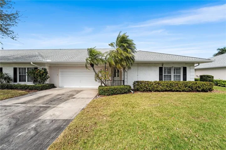 Ranch-style house with an attached garage, brick siding, concrete driveway, roof with shingles, and a front yard