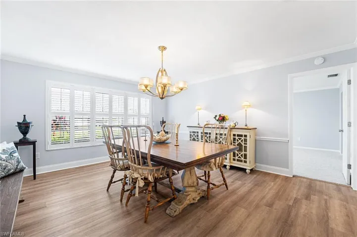 Dining space featuring a chandelier, ornamental molding, wood finished floors, and baseboards