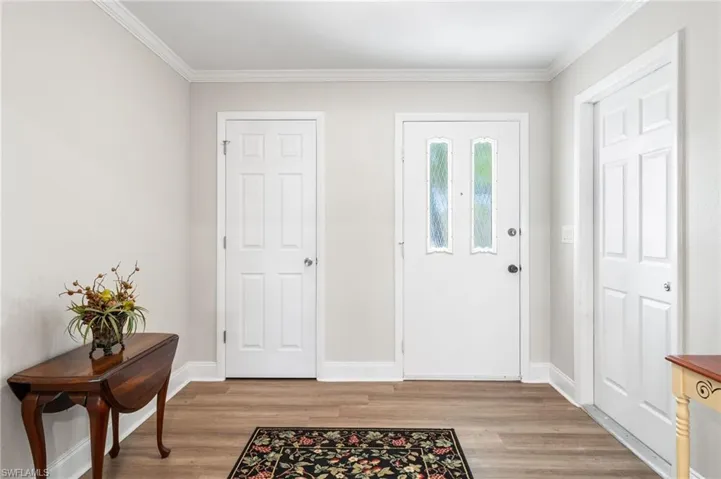 Entryway with crown molding, baseboards, and light wood-style floors