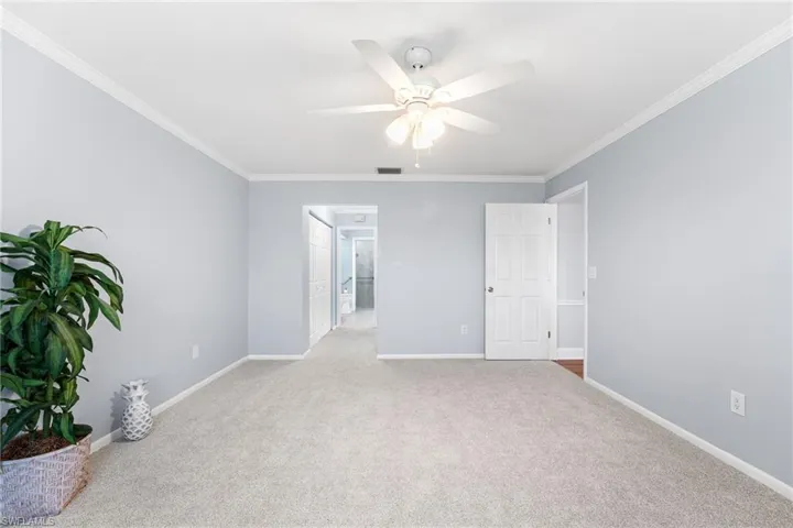 Unfurnished room with light carpet, crown molding, visible vents, and baseboards