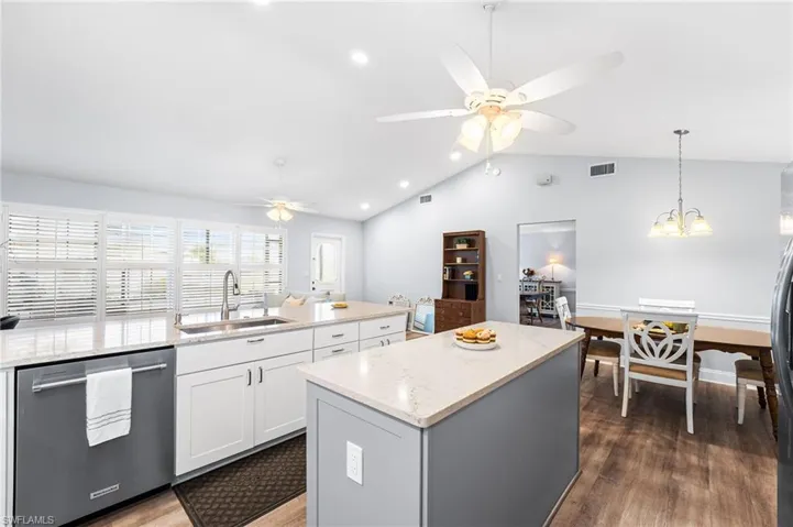 Kitchen featuring stainless steel appliances, dark wood-type flooring, a sink, visible vents, and a center island