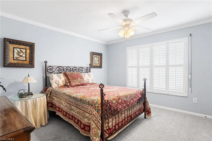 Carpeted bedroom with crown molding, baseboards, and ceiling fan