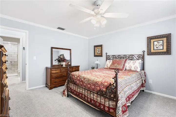 Bedroom featuring visible vents, crown molding, and light carpet