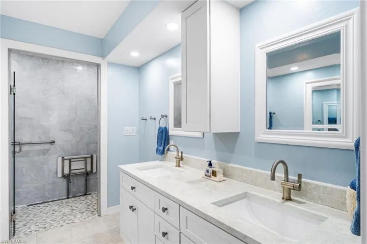 Full bathroom with double vanity, a sink, and a shower stall
