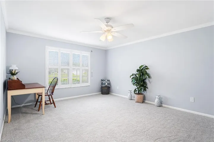 Carpeted office space featuring ornamental molding, a ceiling fan, and baseboards