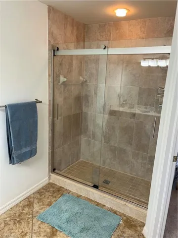 Bathroom featuring a shower stall and tile patterned flooring