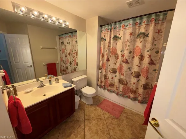 Full bath featuring vanity, shower / bath combo, and light tile patterned flooring