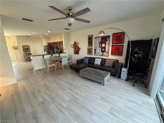 Living area featuring wood tiled floors, ceiling fan, and recessed lighting