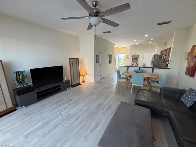 Living area featuring light wood-style floors, a ceiling fan, and recessed lighting