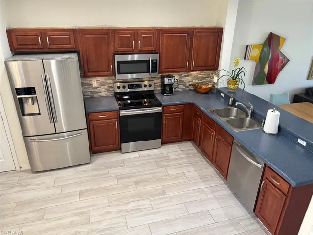 Kitchen with stainless steel appliances, dark countertops, a peninsula, and wood finish floors