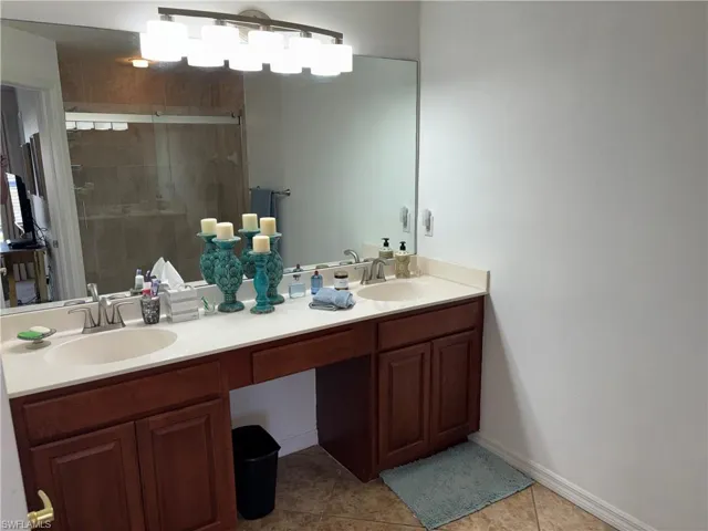 Bathroom with double vanity, a stall shower, and light tile patterned flooring