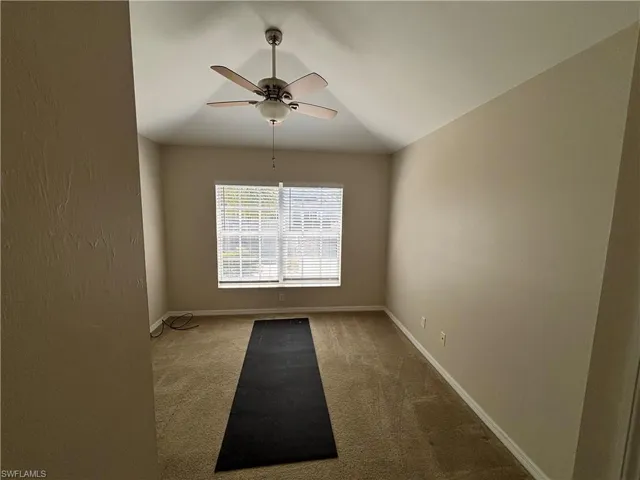 Carpeted empty room featuring a ceiling fan and baseboards