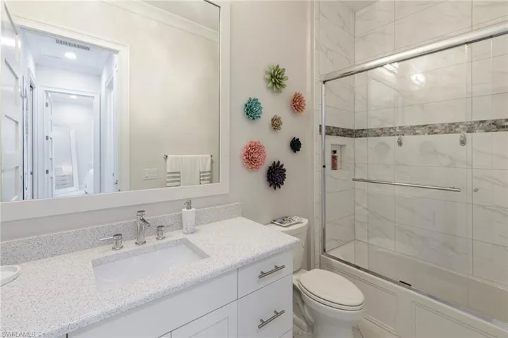 Full bathroom featuring shower / bath combination with glass door, vanity, and toilet