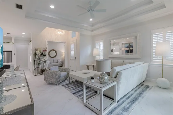 Living room featuring a raised ceiling, ornamental molding, and a wealth of natural light