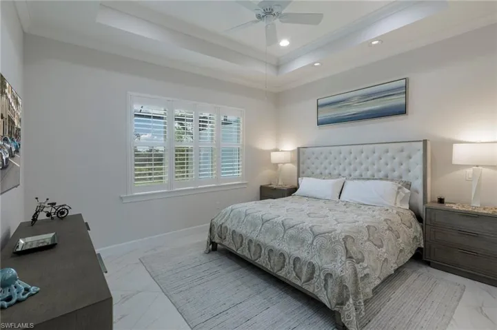 Bedroom with ceiling fan, a raised ceiling, and crown molding