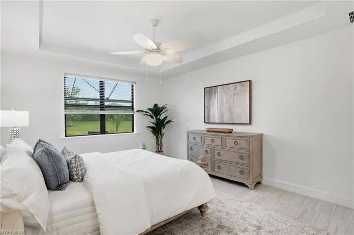 Bedroom featuring a raised ceiling, ceiling fan, and wood finished floors