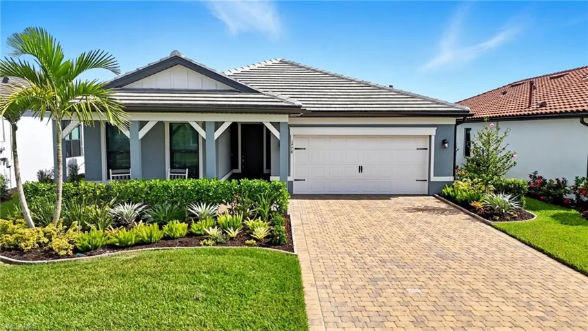 View of front facade with decorative driveway, stucco siding, an attached garage, and a front yard