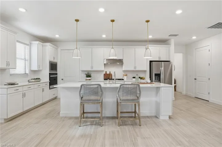 Kitchen featuring decorative backsplash, a breakfast bar, decorative light fixtures, recessed lighting, and white cabinets