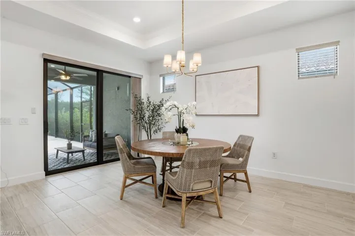Dining area with ornamental molding, a raised ceiling, wood finish floors, ceiling fan, and a chandelier