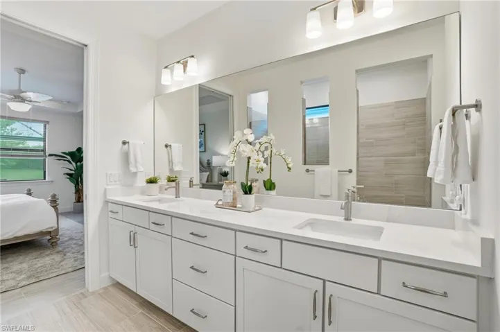 Ensuite bathroom featuring double vanity, a walk in shower, and ceiling fan