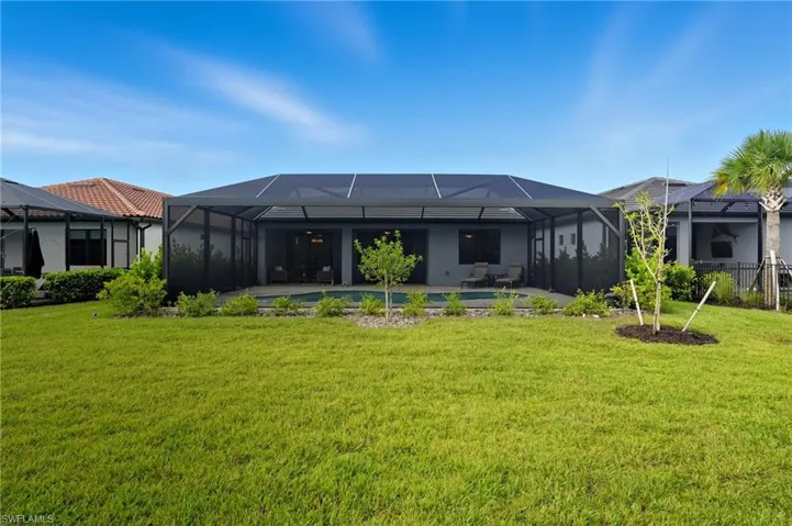 Back of house with glass enclosure, a sunroom, and a lawn