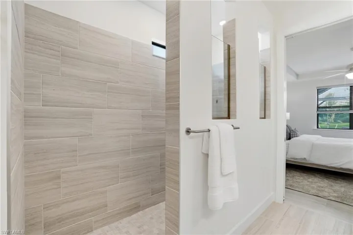 Ensuite bathroom with healthy amount of natural light, walk in shower, and ceiling fan
