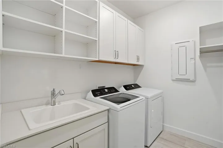 Laundry room featuring light wood-type flooring, cabinet space, separate washer and dryer, and electric panel