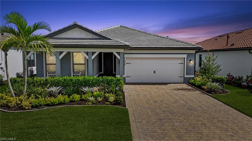 View of front facade with a tile roof, decorative driveway, an attached garage, and a yard