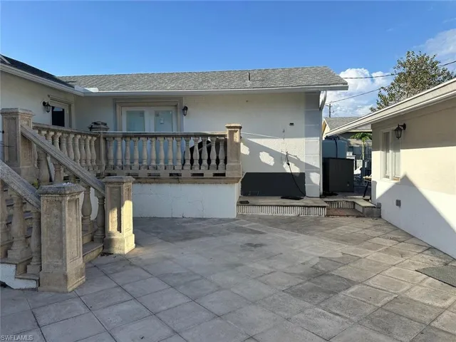 Back of property featuring stucco siding, a shingled roof, a balcony, and a patio area