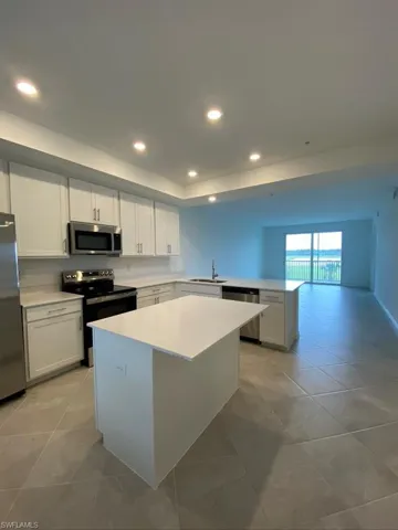 Kitchen featuring stainless steel appliances, white cabinetry, a center island, recessed lighting, and a peninsula