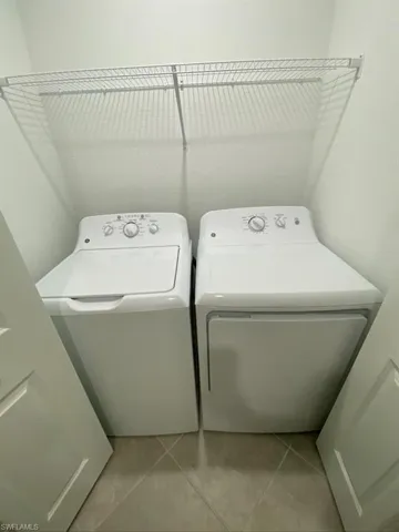 Washroom with light tile patterned floors and independent washer and dryer