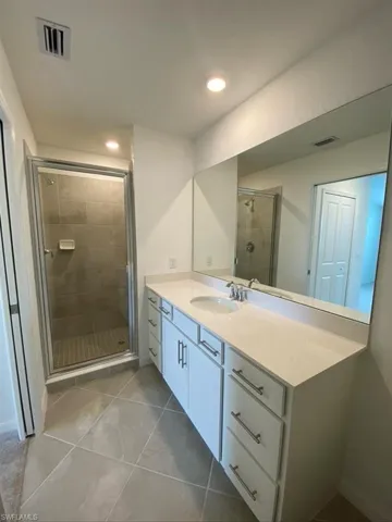 Bathroom with vanity, a shower stall, light tile patterned flooring, and recessed lighting