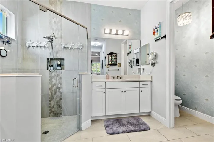 Bathroom featuring wallpapered walls, vanity, a stall shower, and light tile patterned floors