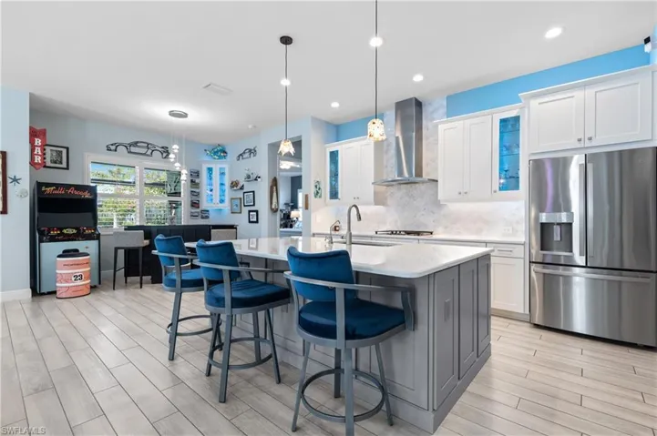 Kitchen with stainless steel appliances, an island with sink, a kitchen bar, hanging light fixtures, and dual tone cabinetry