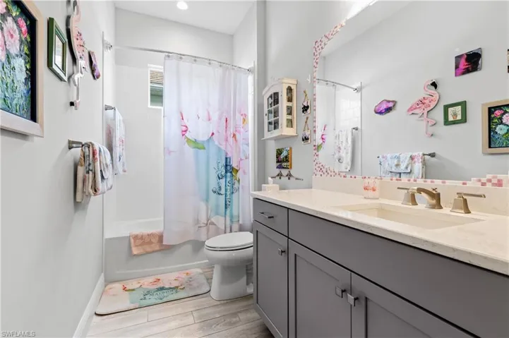 Bathroom with vanity, shower / tub combo, and wood tiled floors