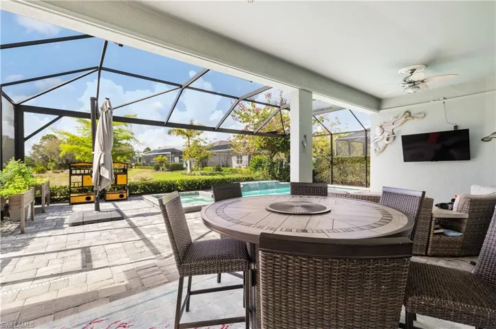 View of patio featuring an outdoor pool, glass enclosure, a sunroom, outdoor dining area, and ceiling fan