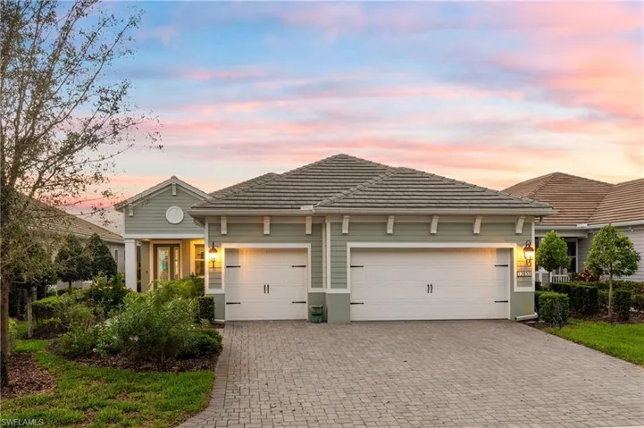 View of front of property featuring a garage, decorative driveway, a tiled roof, and a yard