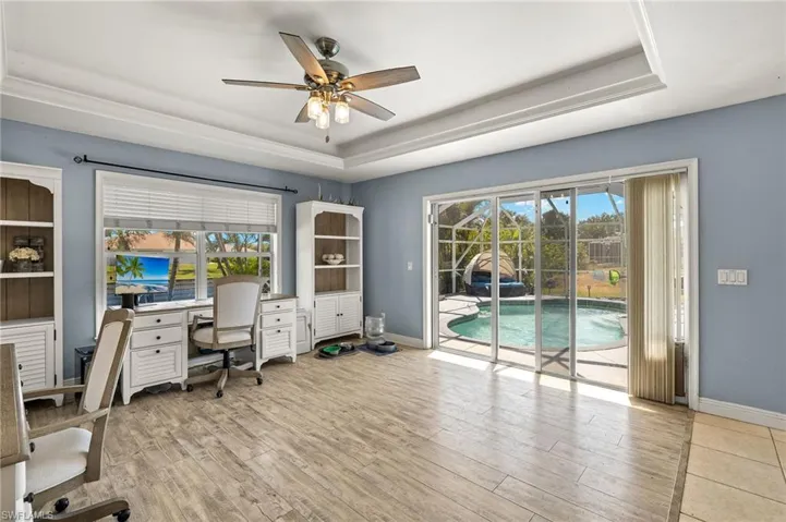 Office space featuring plenty of natural light, ceiling fan, a tray ceiling, and light wood-type flooring