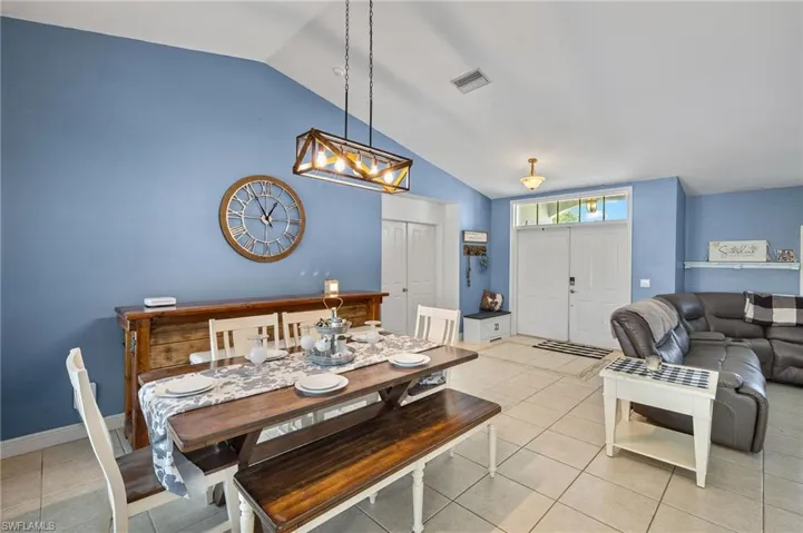 Dining room featuring visible vents, baseboards, lofted ceiling, an inviting chandelier, and light tile patterned flooring