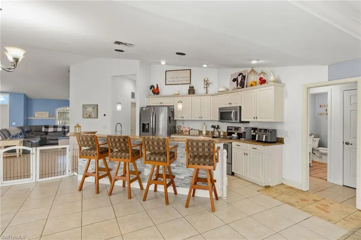 Kitchen with open floor plan, a sink, light tile patterned floors, hanging light fixtures, and stainless steel appliances