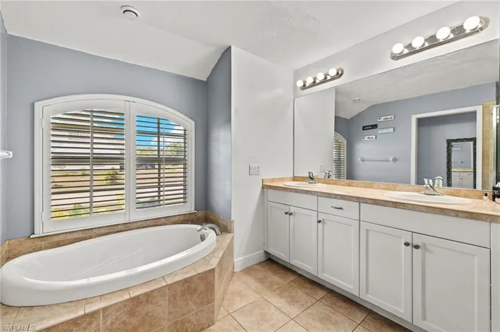 Bathroom with a garden tub, a sink, tile patterned floors, and double vanity